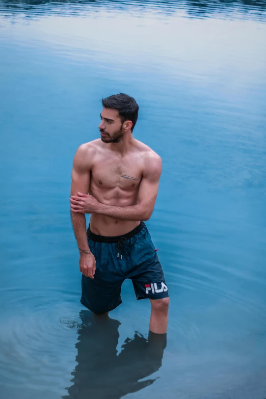 a man stands in shallow water with his hands on his chest