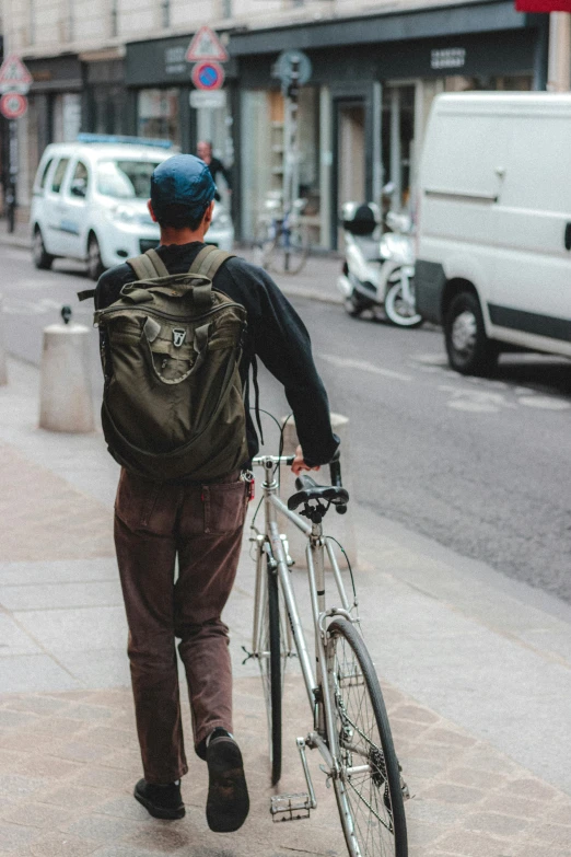 there is a man walking down the street with his bike