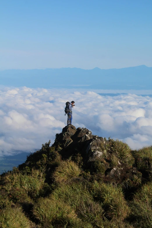 a person on top of a large rock with a backpack