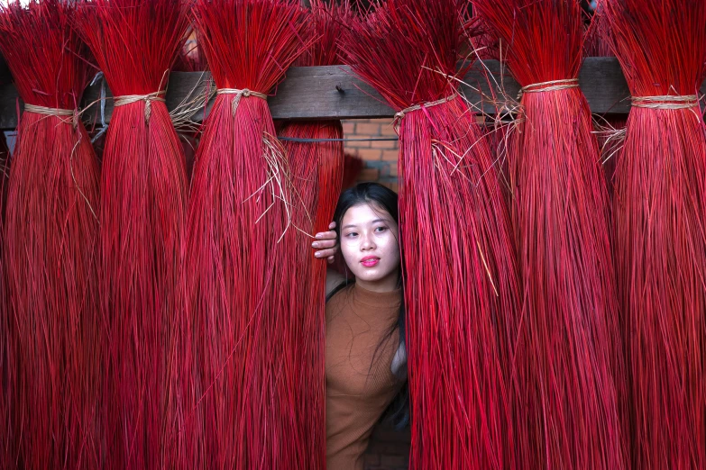 an asian woman peeking out from the curtain with red threads strung across it