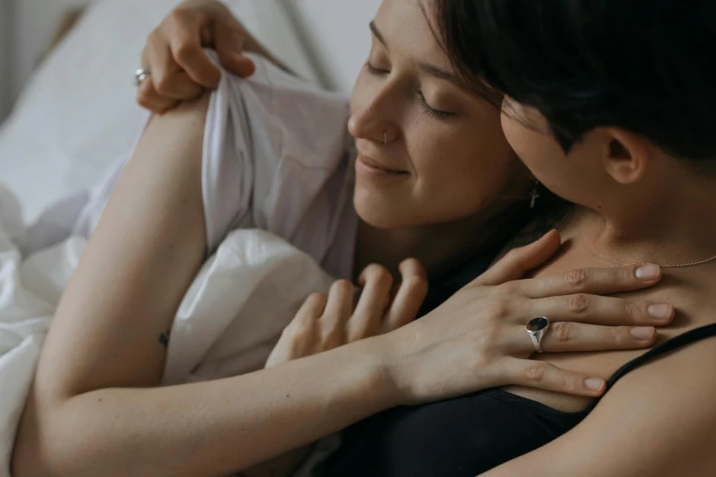 a woman laying in bed hugging another person