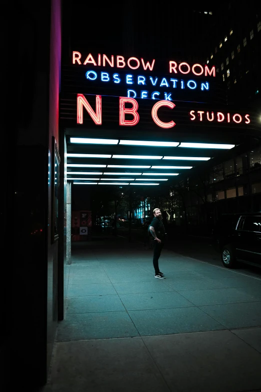 a man is standing under the neon sign