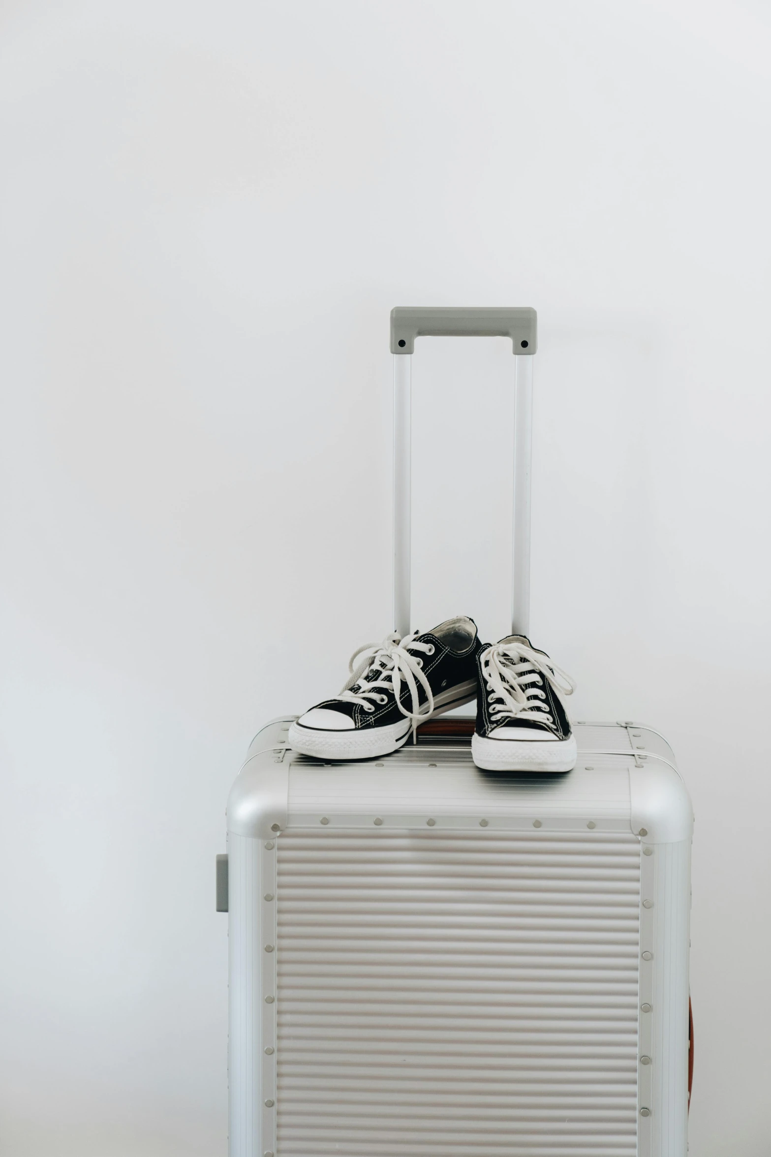 a white suitcase with shoes on top and a black and white bag