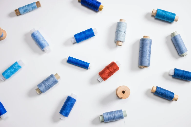 some spools of thread and needles on a white surface