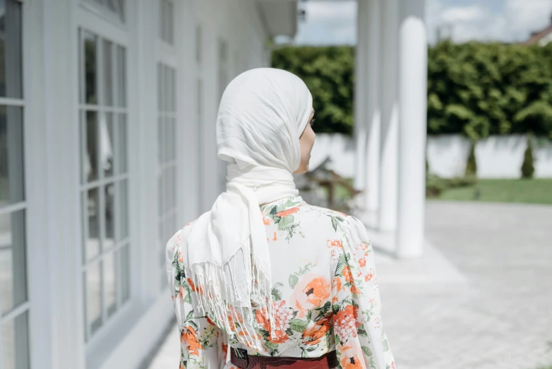 a woman in white head covering walking down a hallway