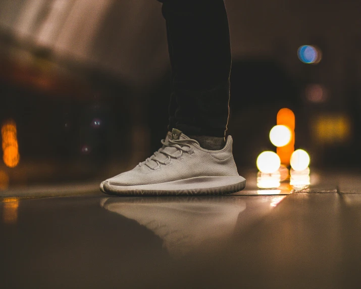 a person wearing white sneakers standing on a wood floor