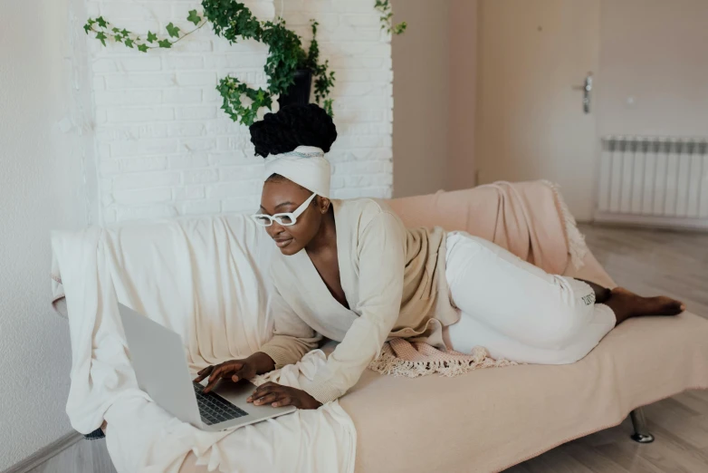 a woman sitting on a bed using a laptop