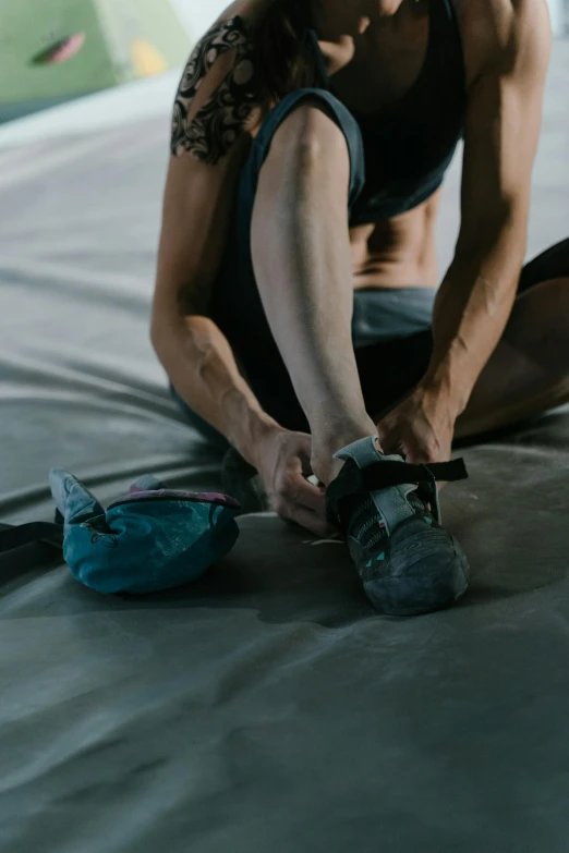 a man sitting down in front of a sleeping bag while tying sneakers