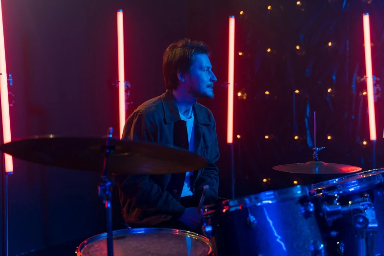 a man plays on drums in front of a dark background