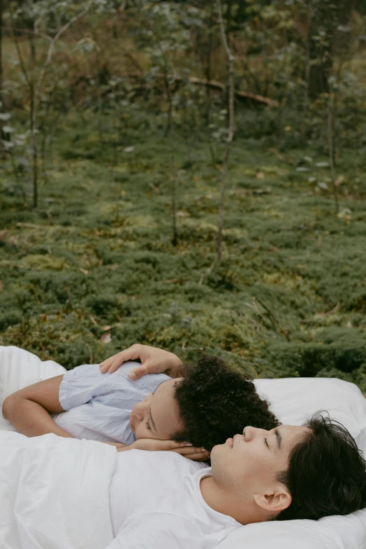 a man and woman are laying down on the bed