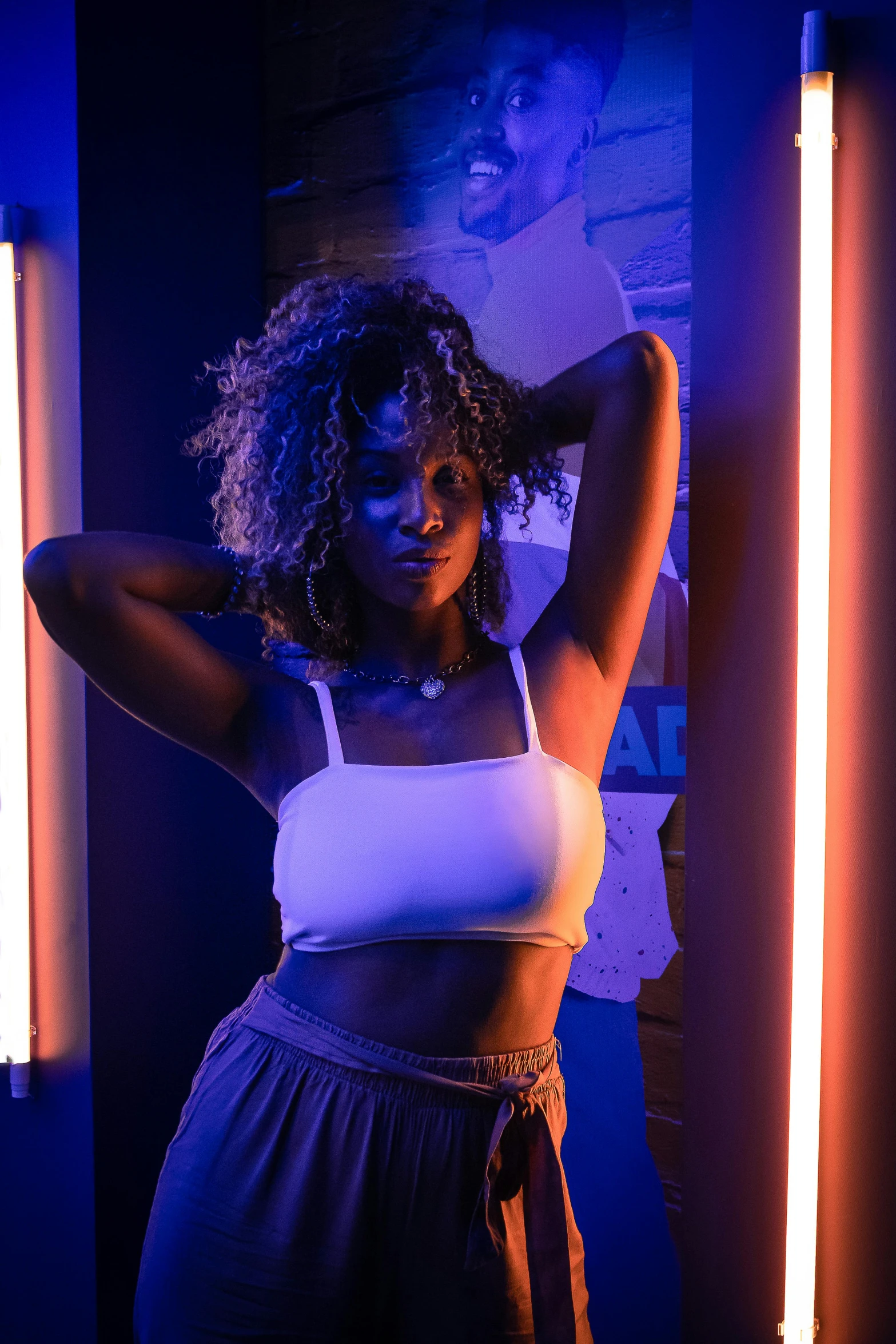 a woman in white top and black shorts standing near column lights