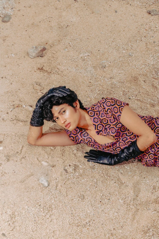 a woman lies on the sand while wearing black gloves