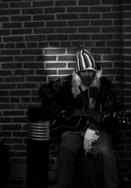 man sitting on a stool playing the guitar