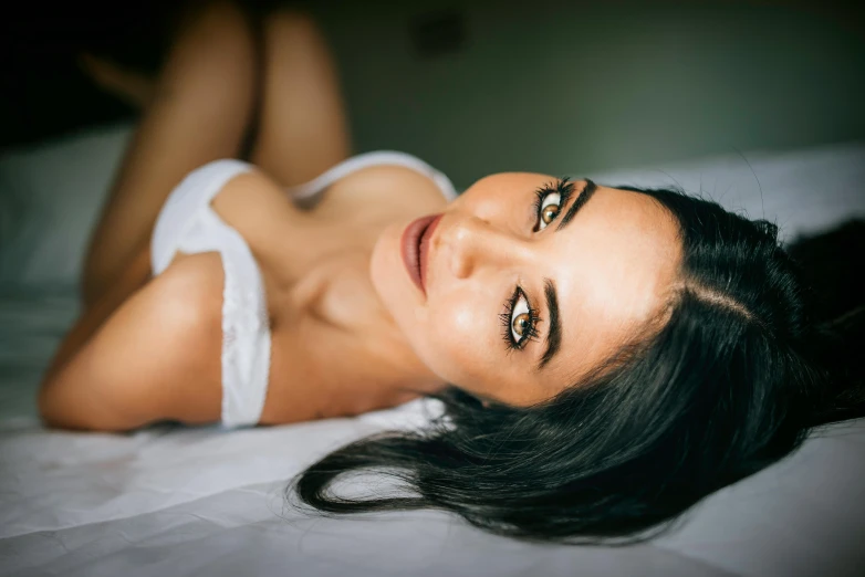 a very cute woman laying on a bed with her eyes half open