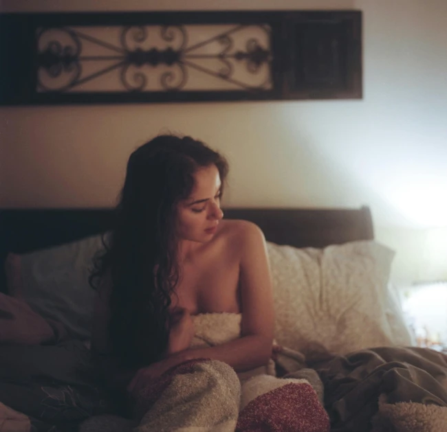 a woman sitting on top of a bed in front of a window