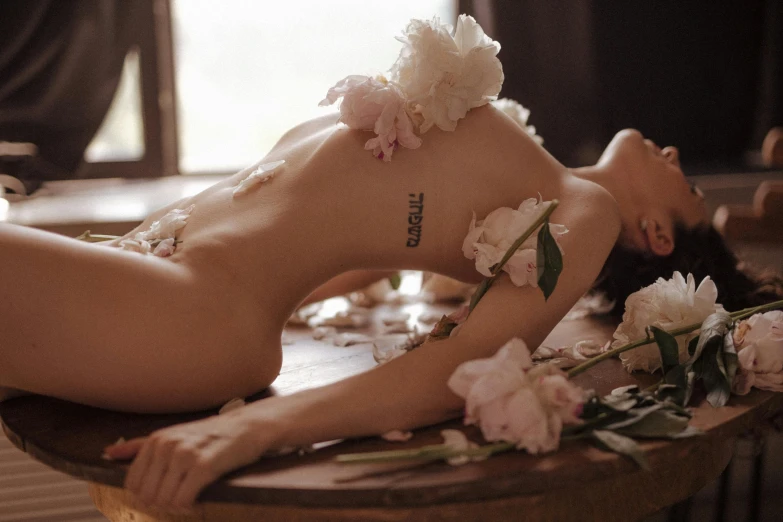 a woman laying on a table with flowers around her