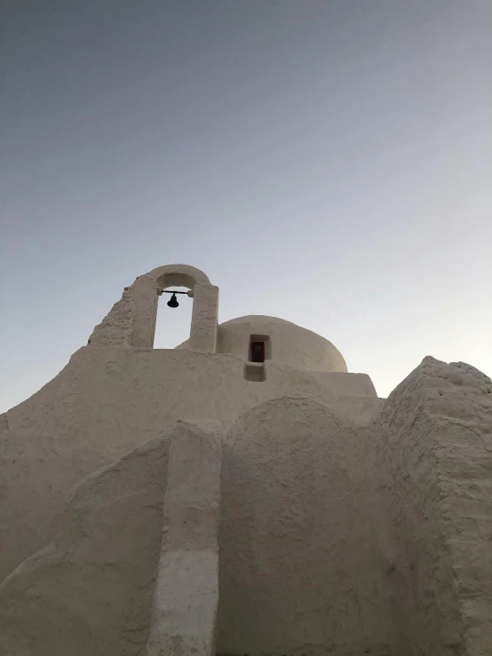 white architecture with arched doorway and bell