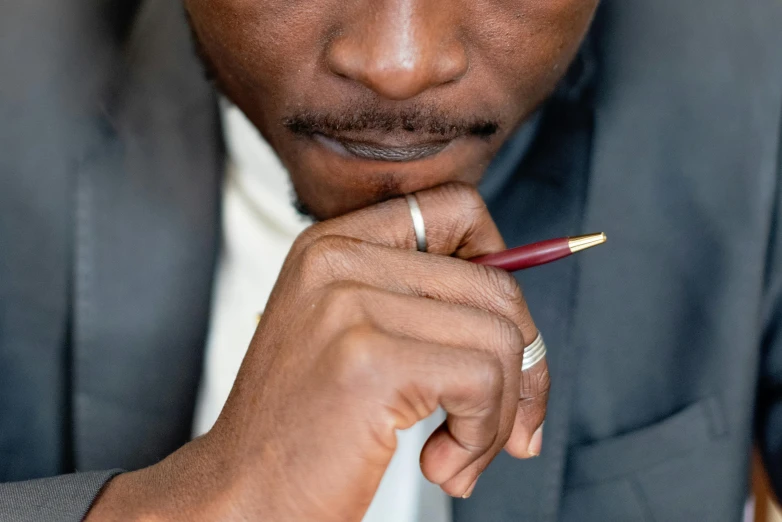 a man with dark hair in a suit holding a pen