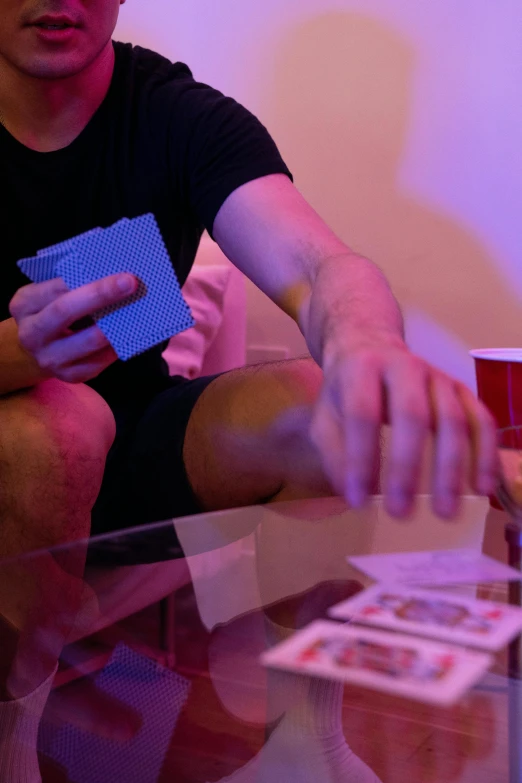 a man is holding a playing card and sitting in front of him