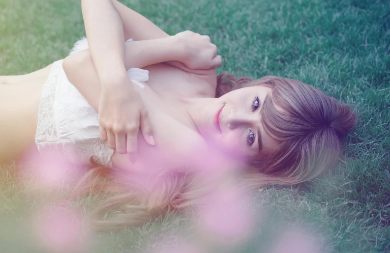 a young woman laying in the grass wearing a bathing suit