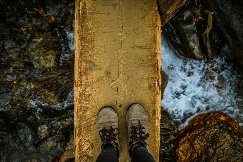 person with boots standing on a ledge near water