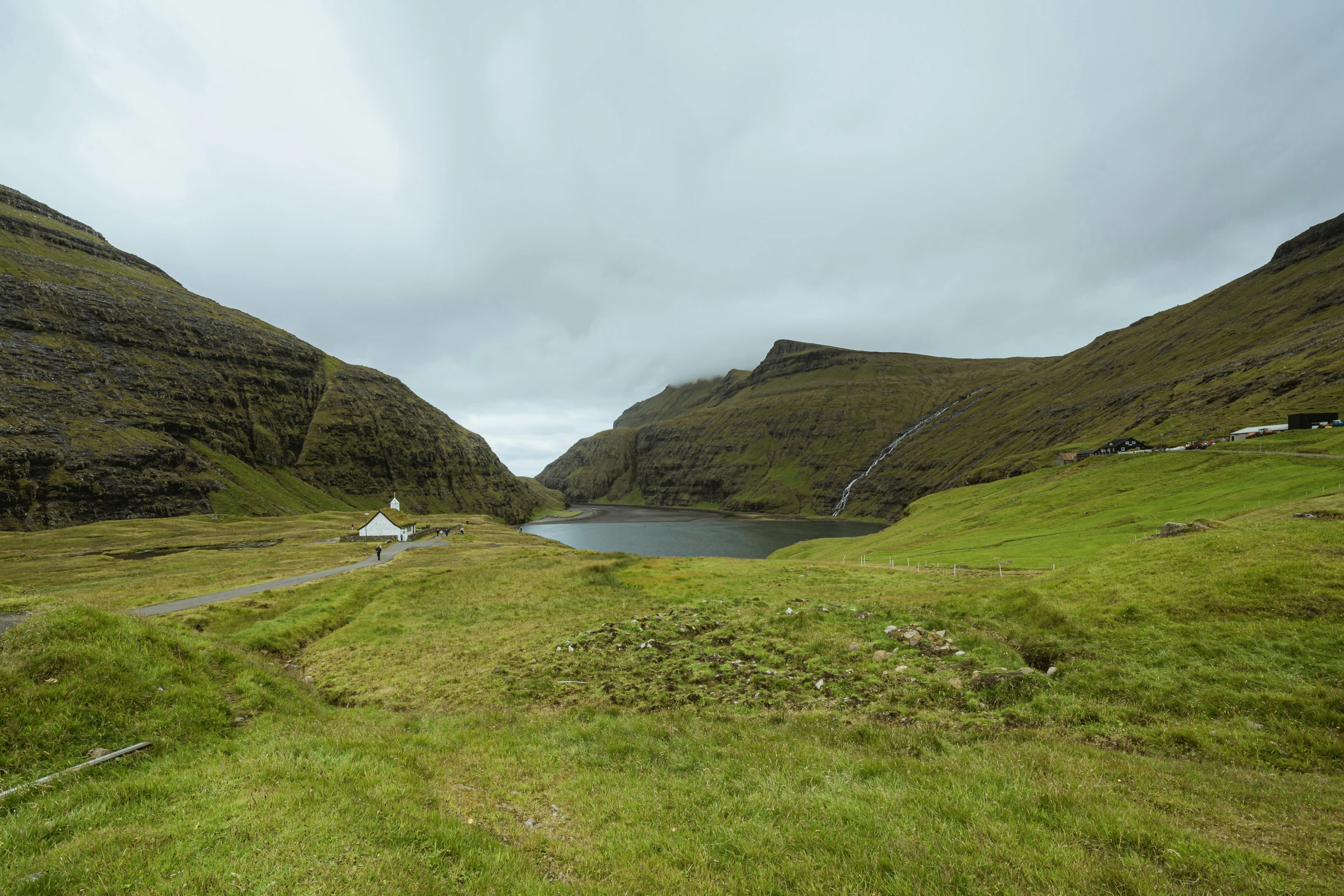 an empty mountain with a lake and grassy fields