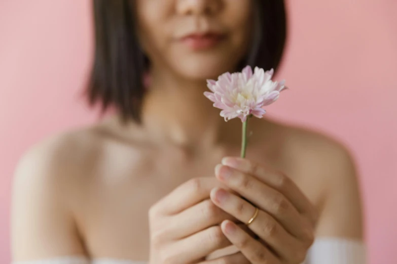 a woman holding onto a pink flower that is blooming