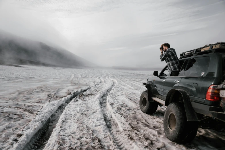 a guy is sitting on his truck in the snow