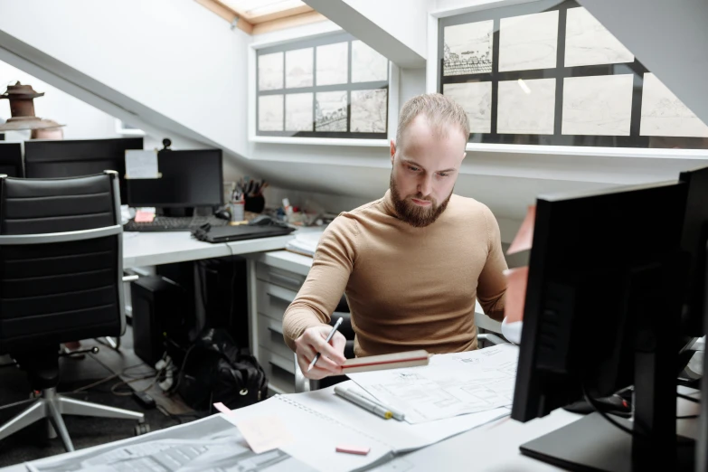 a man with beard working on paper in his office