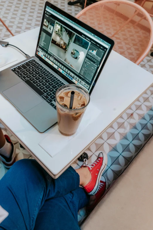 someone sitting at a white table with their lap top open