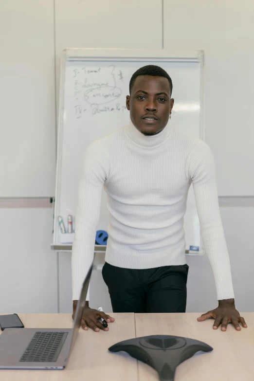 a man is standing next to a laptop in an office