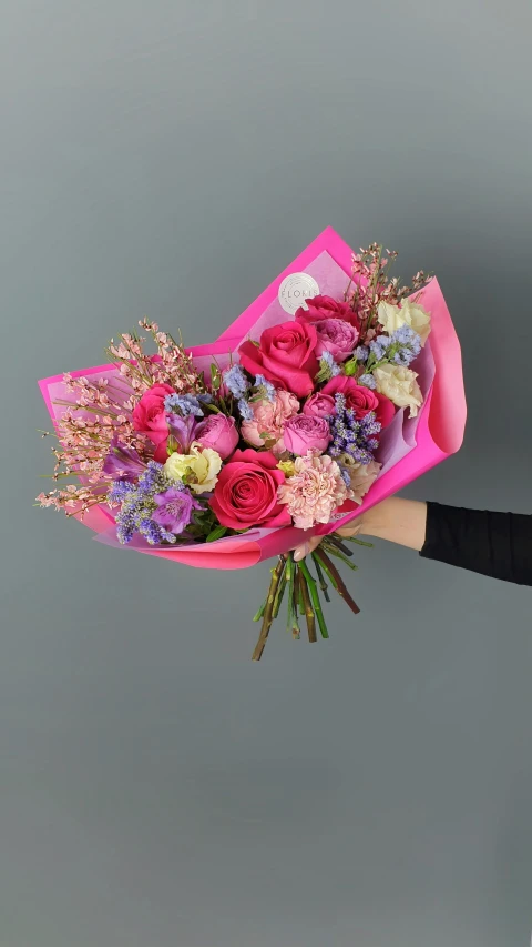 someone holding up a bouquet of pink and purple flowers