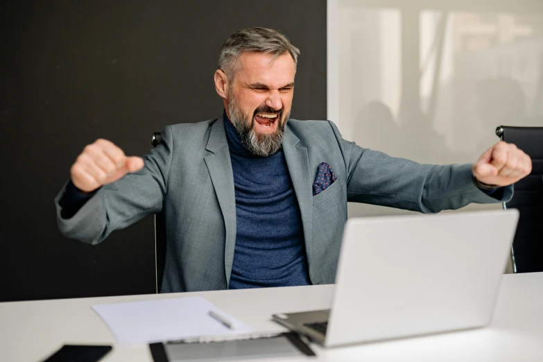 a man is laughing and using his laptop