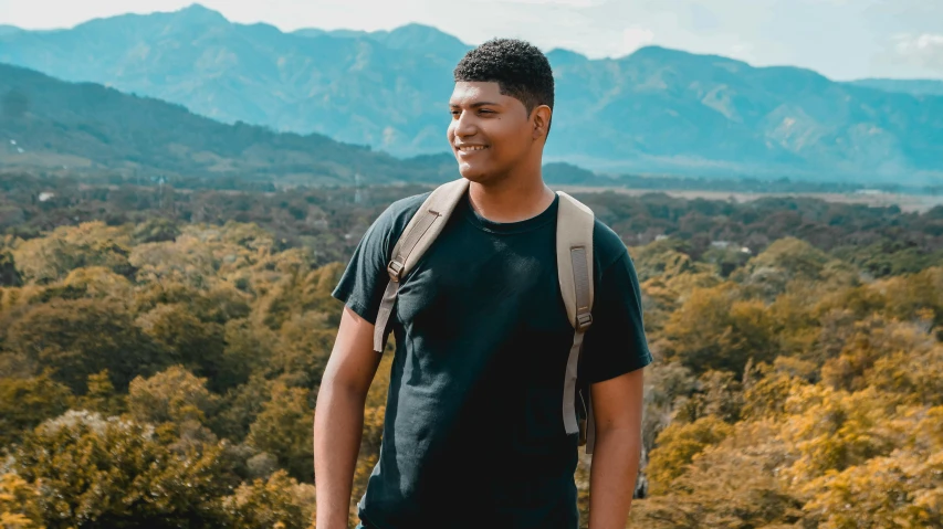 young male hiking in mountains with backpack and a view