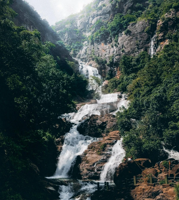 several large waterfall cascading over a forest filled mountain