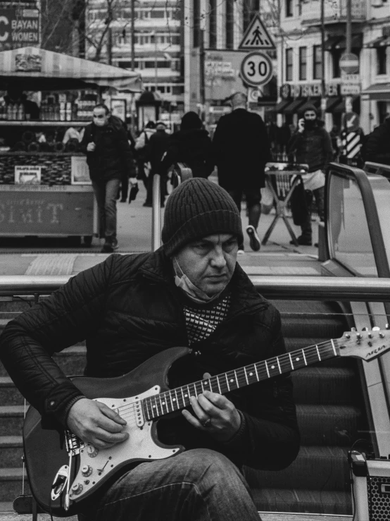 a person playing an electric guitar on a city street