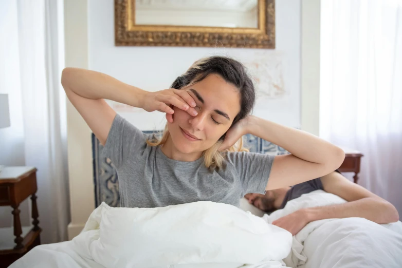 the man and woman are in bed, the woman is holding his head in pain