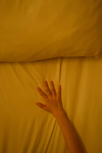 a hand reaching out from under a bed spread