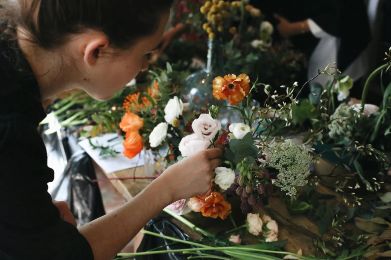 a woman arranging and arranging flowers on a table