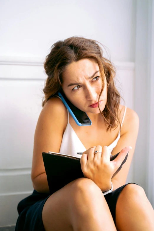 a beautiful young woman sitting on a chair while talking on a cell phone