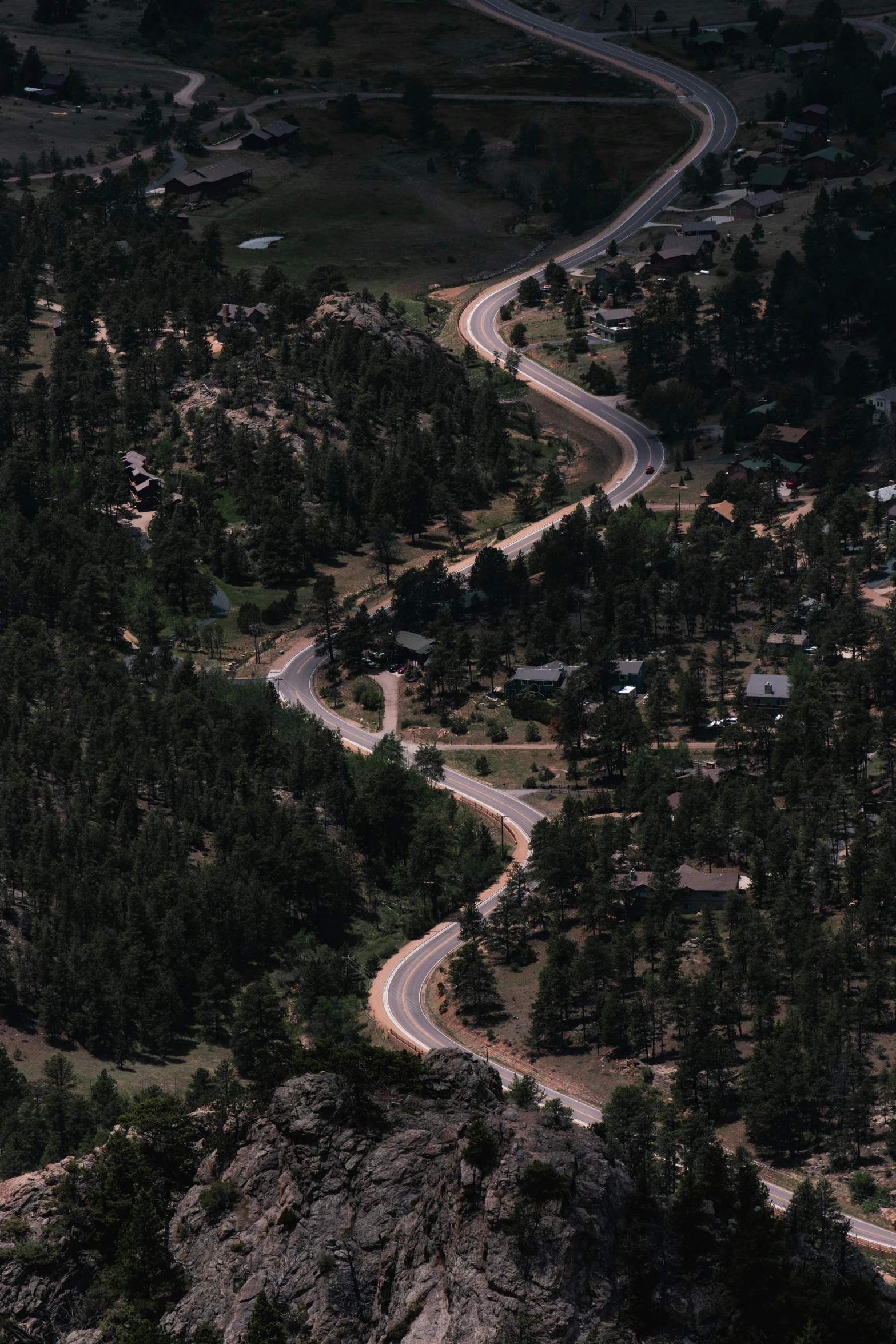 a winding mountain road that has trees and bushes on the side