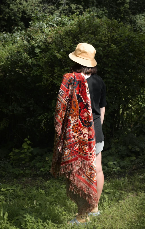 a lady standing in grass wearing a red cloth