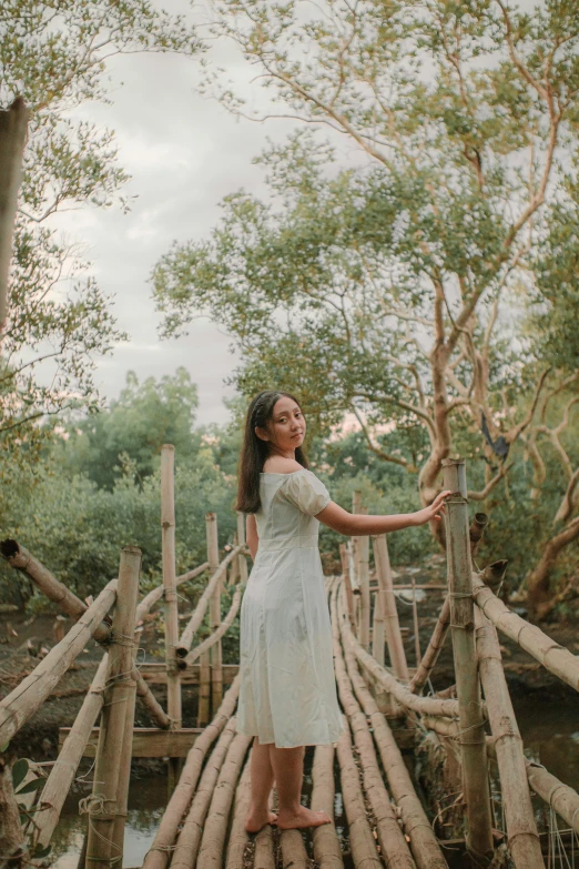 a woman poses on a bridge over a small stream