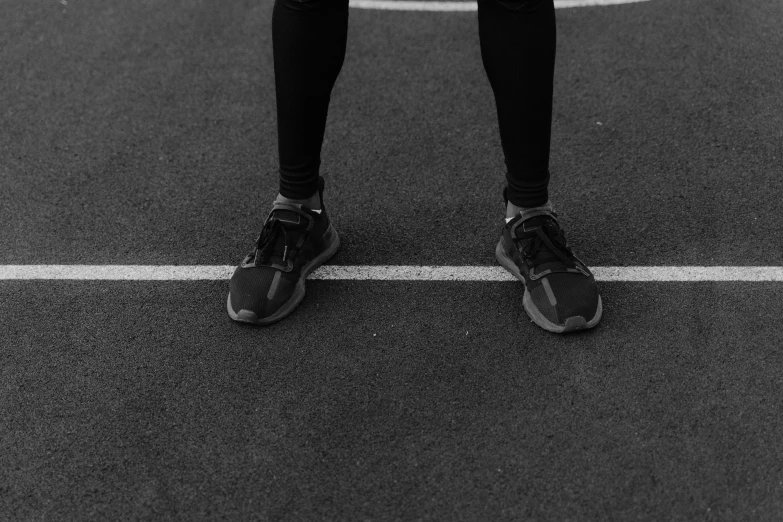 a man in black pants and sneakers standing on the road