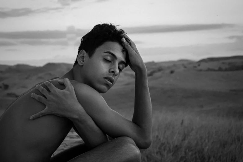 black and white po of a man sitting in the middle of a field