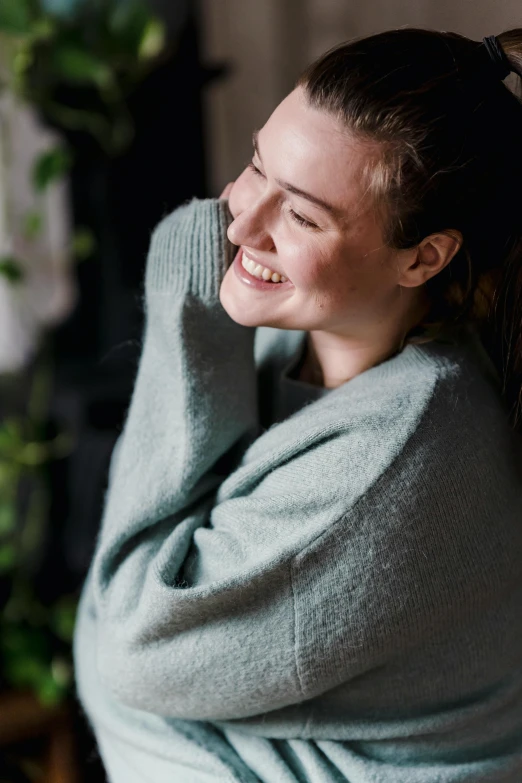 a smiling woman with a gray sweater sitting down