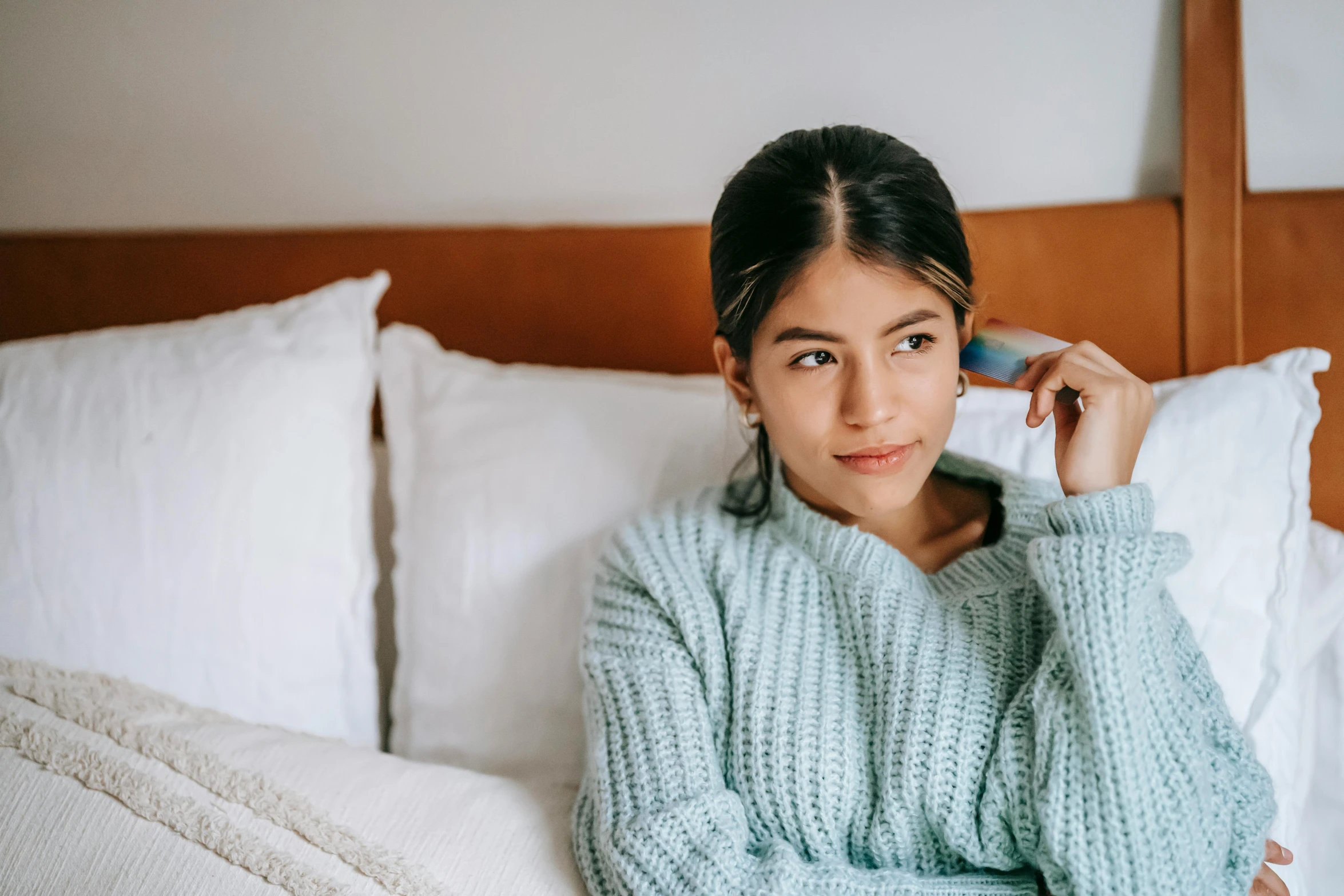 a woman sitting in bed talking on a phone