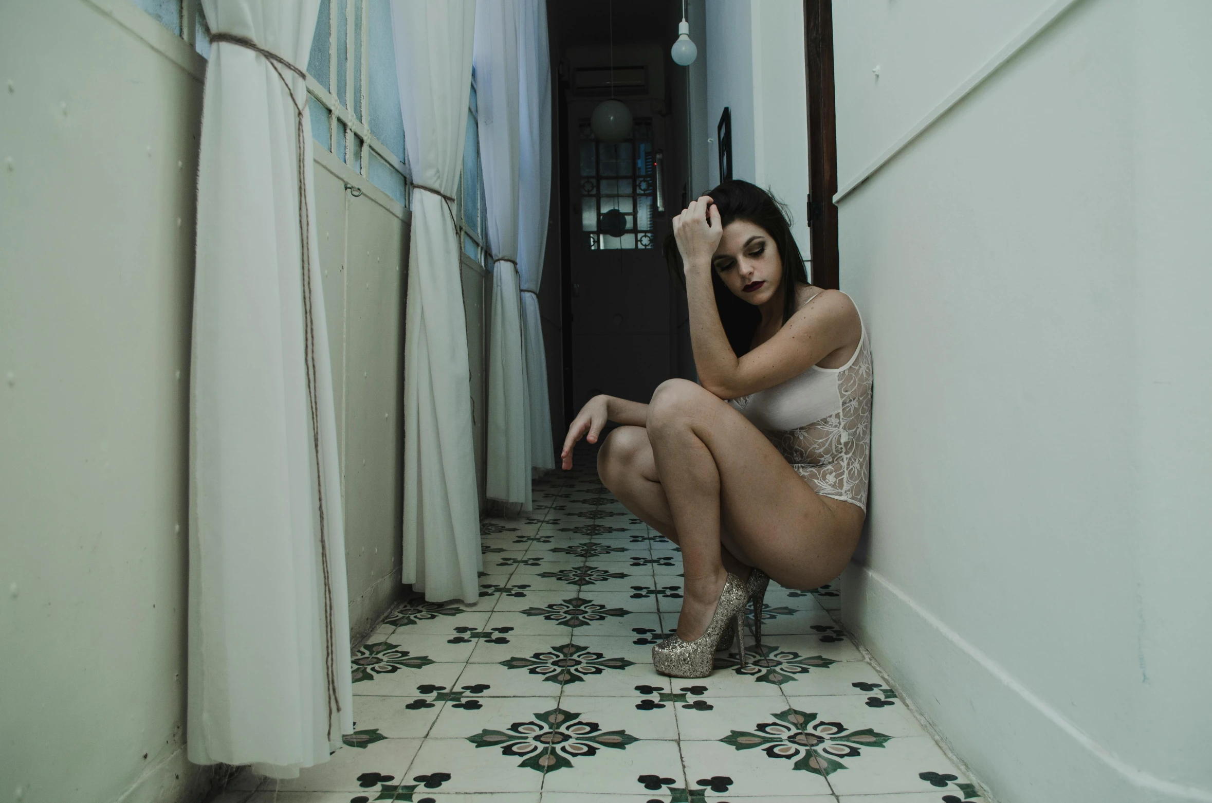 a woman in white clothing sitting on a tiled floor