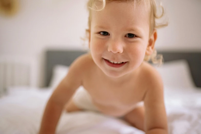 a baby girl laying on the bed with her hair blowing in the wind