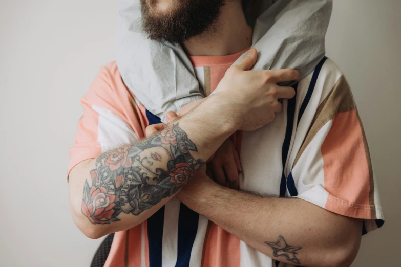 a man with a tattooed arm and an orange t - shirt on holding a cell phone